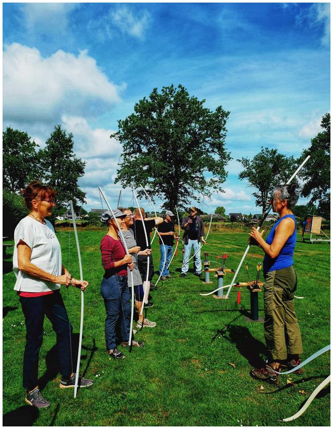Gruppe Bogenschützinnen mit Übungsbögen